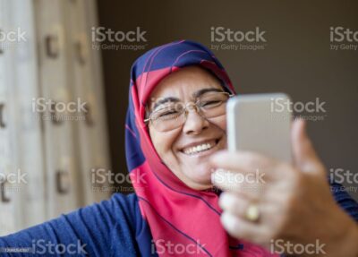 Senior muslim woman wearing a headscarf taking a selfie, indoors